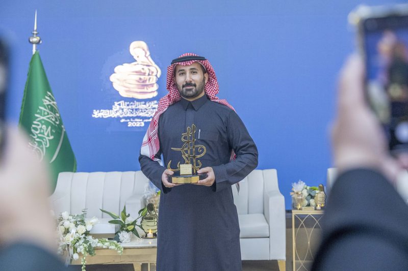 Dr. Alsaleh on stage with the trophy